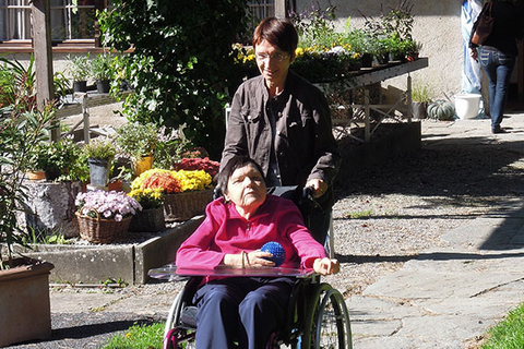 Eine Frau spaziert mit einer Frau im Rollstuhl