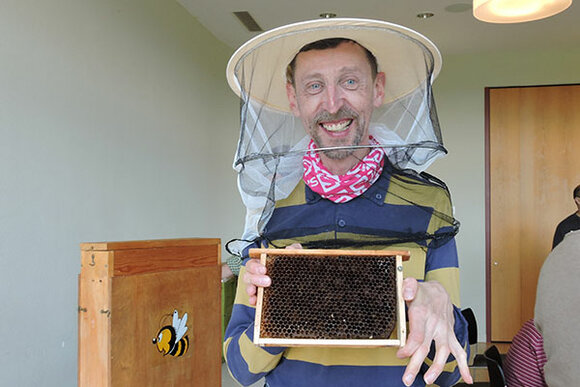 Ein Mann mit einer Behinderung zeigt eine Bienenwabe
