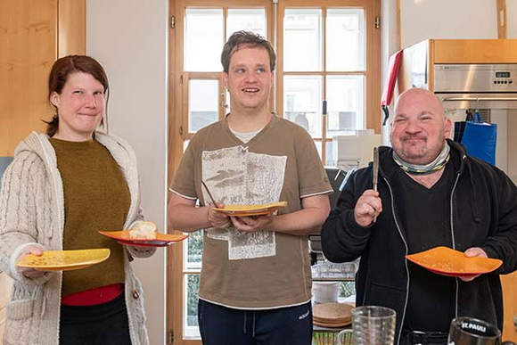 Eine Frau und zwei Männer mit Geschirr in der Küche
