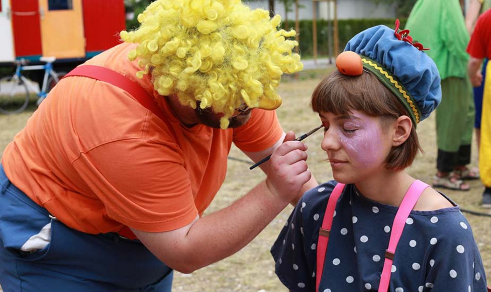 Ein Bewohner, als Clown verkleidet, schminkt eine Zirkus Artistin