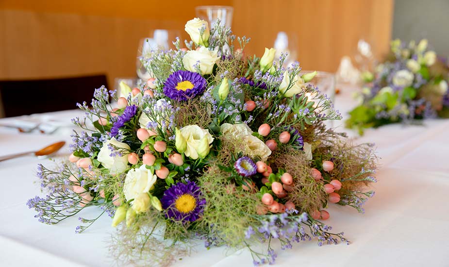 Edles Blumengestetz auf schön gedecktem Tisch eines Leidmahls