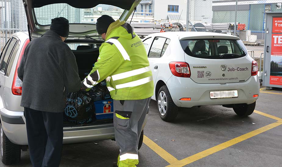 Ein Mitarbeiter der Schneider Umweltservice AG und ein Kunde beim Ausladen eines Fahrzeuges