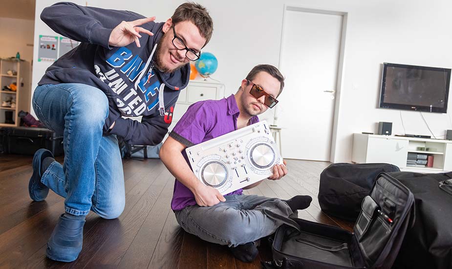 Zwei junge Männer im Wohnzimmer mit portablem DJ-Pult