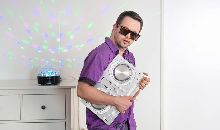 junger Mann mit Sonnenbrille und portablem DJ-Pult in der Wohnung
